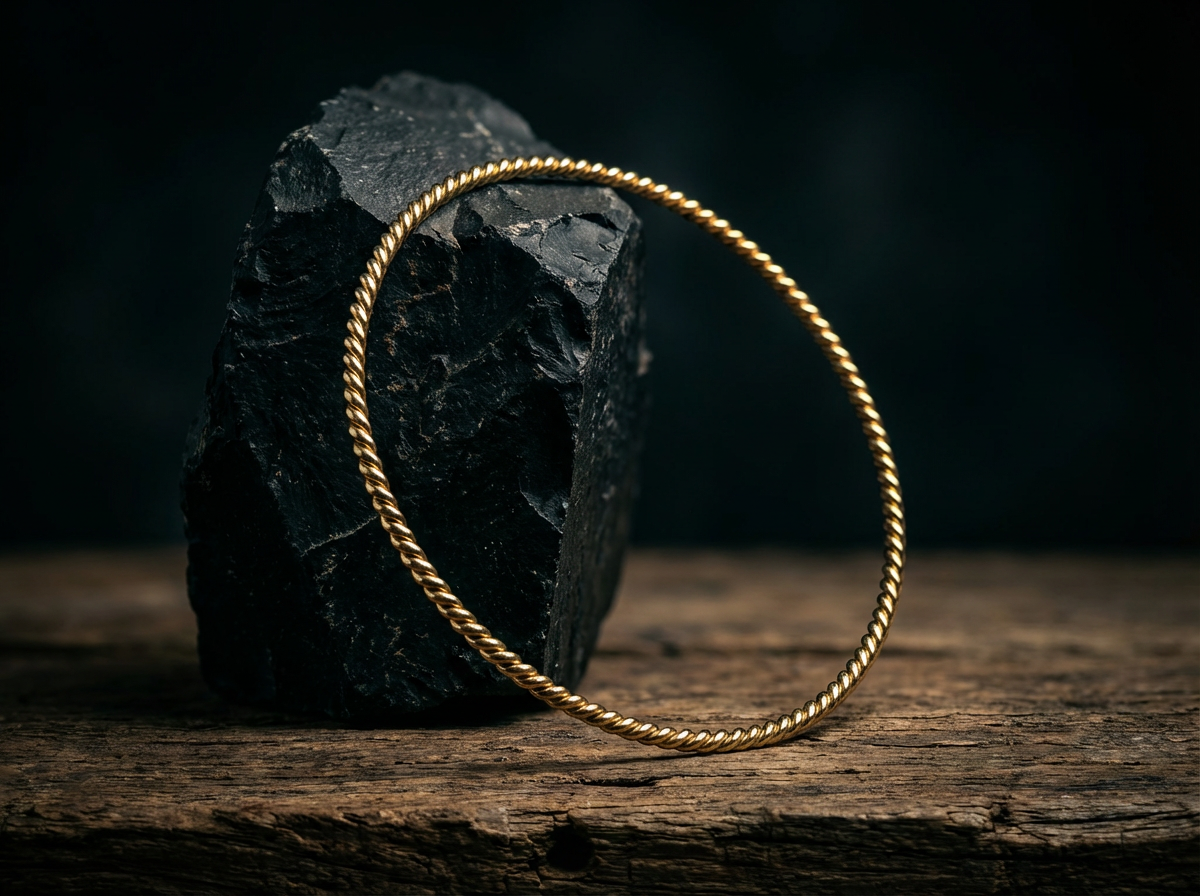 vergoldet 24 Karat Lost Cubit Tensorring Classic lehnt an einem dunklen Stein (3mm). Produktbild