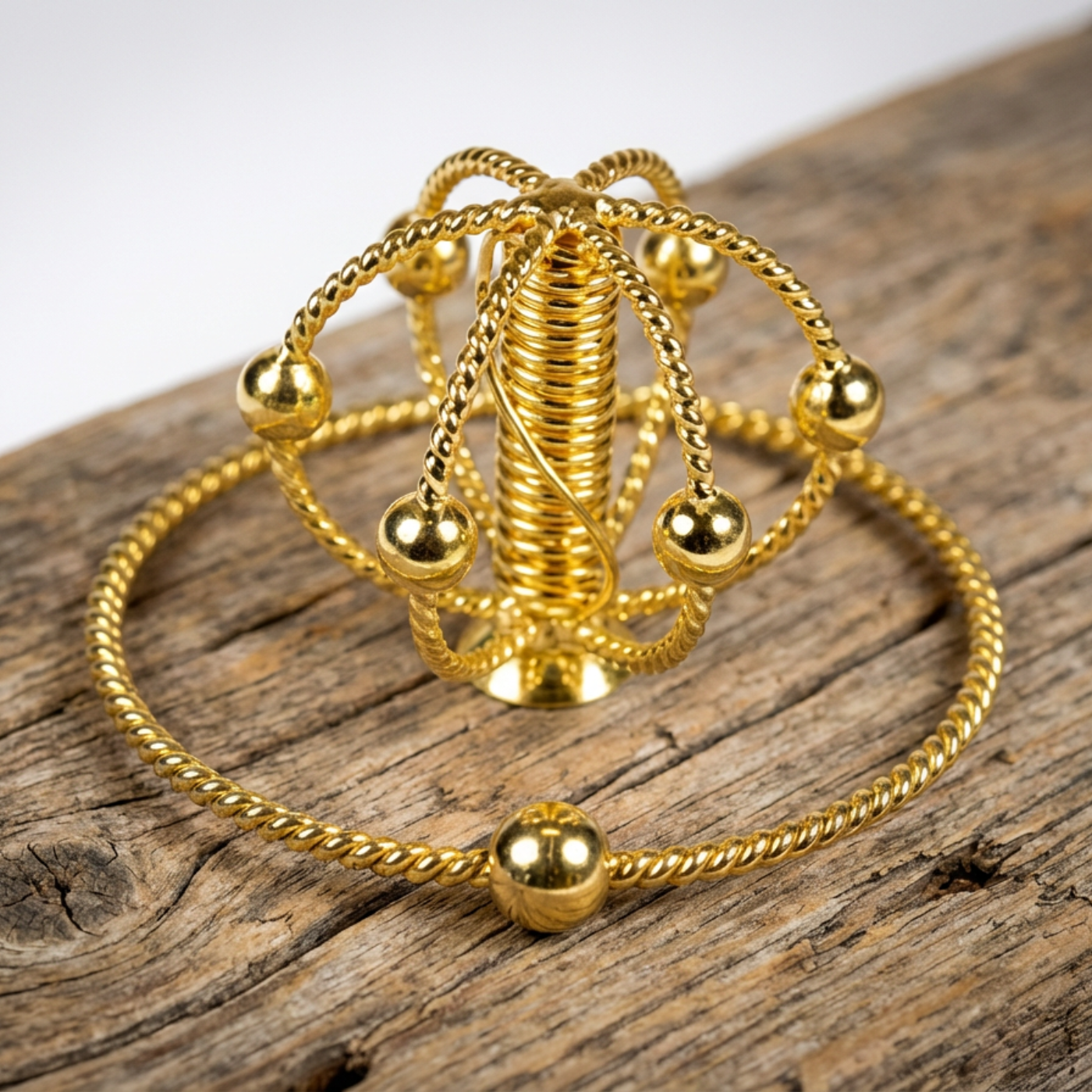 Harmonizer mit einem Sacred Cubit Tensorring vergoldet liegen auf Holz. Produktfoto